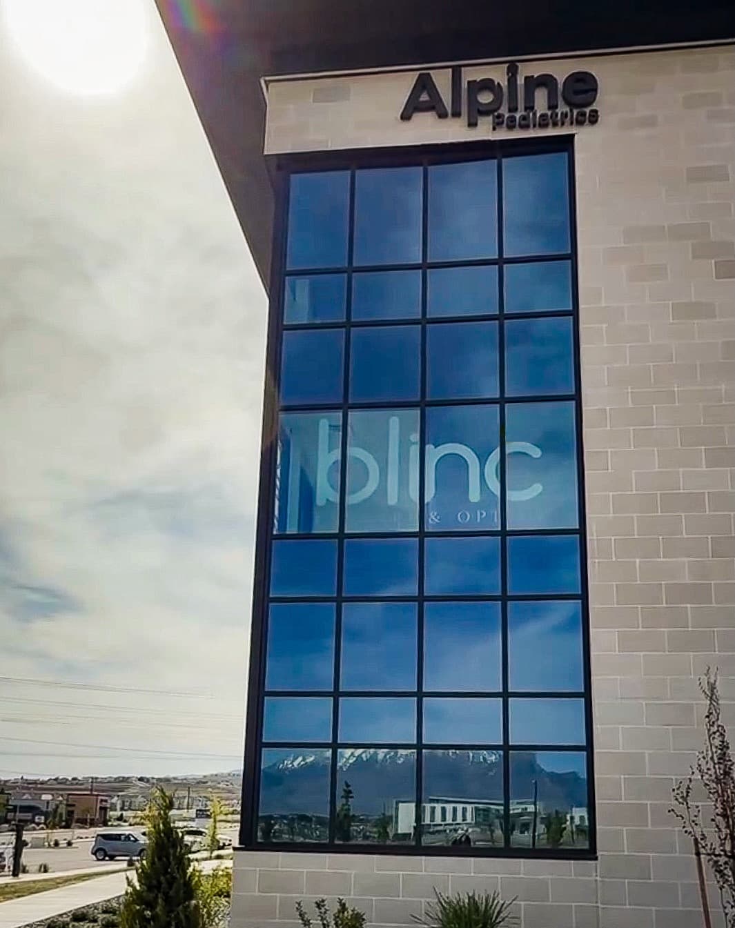 Blinc Eyecare storefront in Lehi — look for the tall windows under the Alpine Pediatrics sign, with the Wasatch mountains reflected in the glass